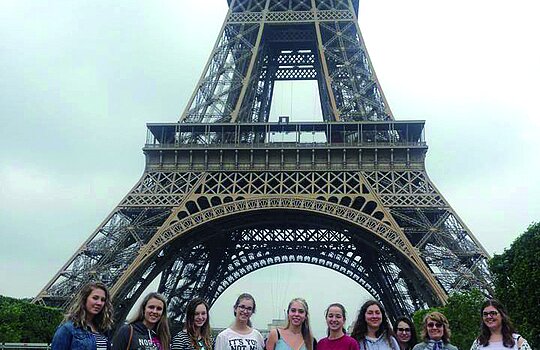 Un groupe d'étudiants posent devant la tour Eiffel à Paris.