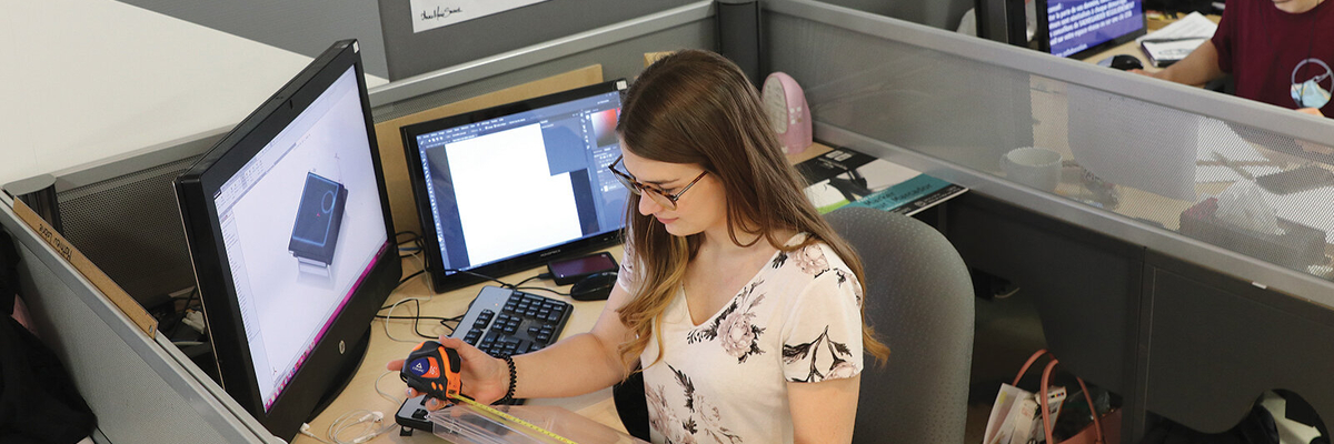 Une étudiante en classe devant l'ordinateur prend des mesure d'un objet de plastique.