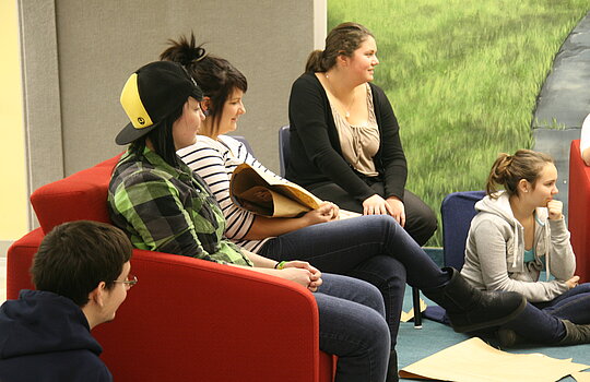 Des étudiants assis dans un fauteuil en discussion.