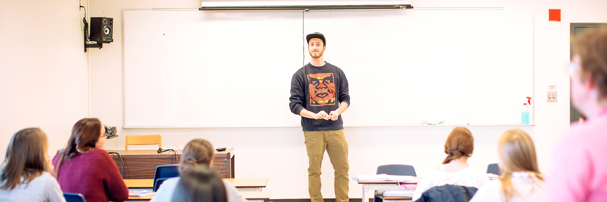 Un étudiant fait une présentation devant ses camarades en classe.
