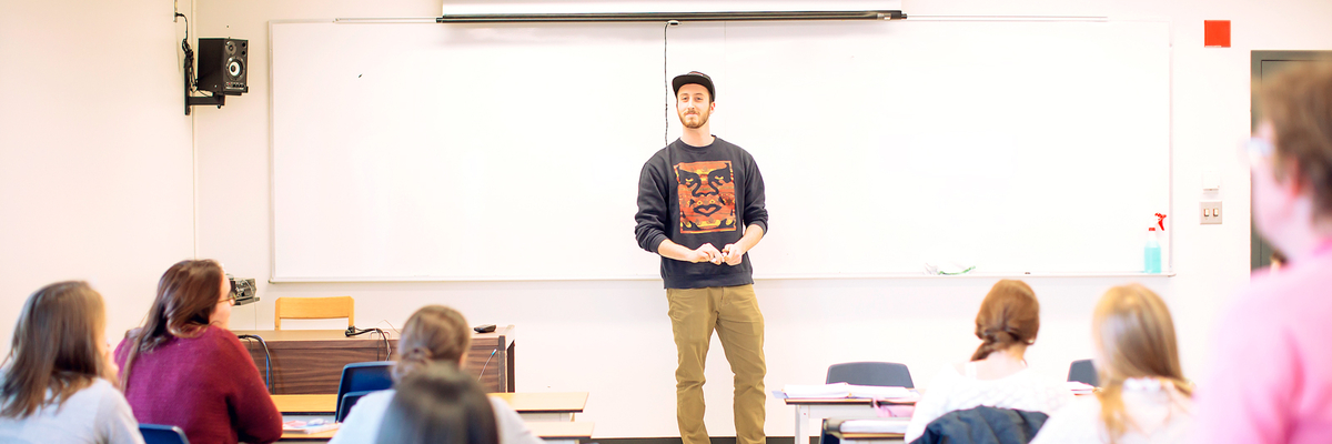 Un étudiant fait une présentation devant ses camarades en classe.