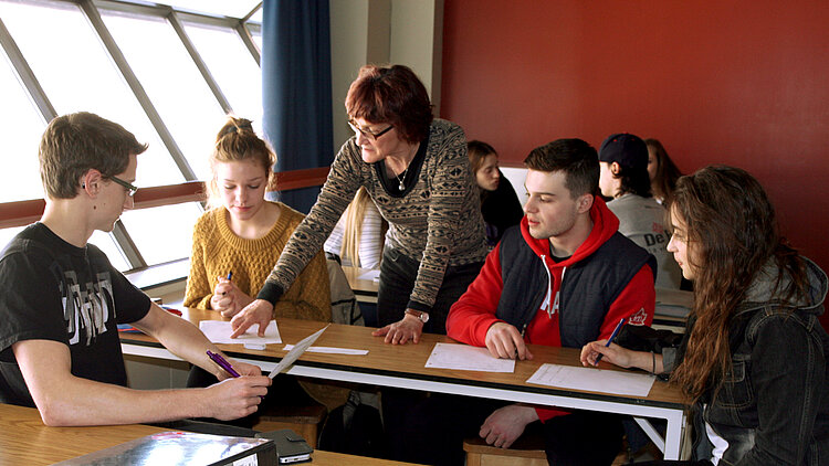 Une professeure donnes des explications à ses étudiants à une table.