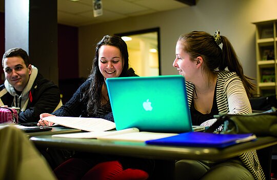 Deux étudiantes souriantes discutent en classe.