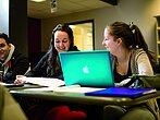 Deux étudiantes souriantes discutent en classe.