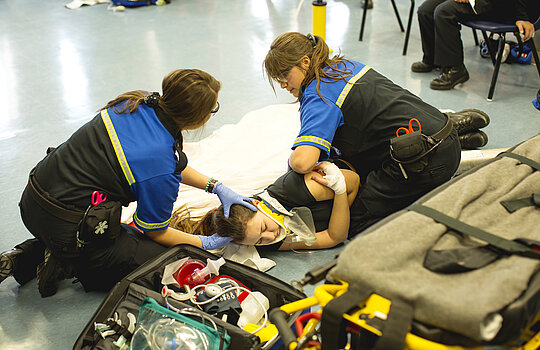 Deux étudiantes tournent sur le côté une étudiante qui porte un collier d'immobilisation.