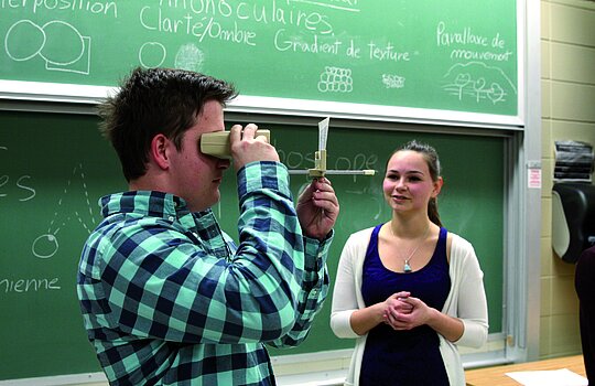 Un étudiant regarde à travers un instrument sous les yeux de sa camarade.