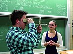 Un étudiant regarde à travers un instrument sous les yeux de sa camarade.