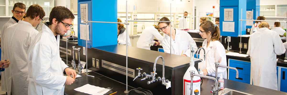 Des étudiants avec sarreaux et lunettes en laboratoire.