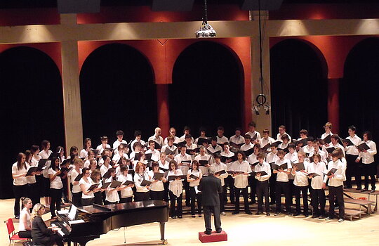 Une chorale performe sur scène accompagnée au piano.