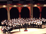 Une chorale performe sur scène accompagnée au piano.