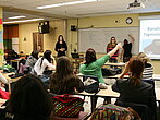 Une classe avec des étudiants qui lèvent la main pour poser une question.