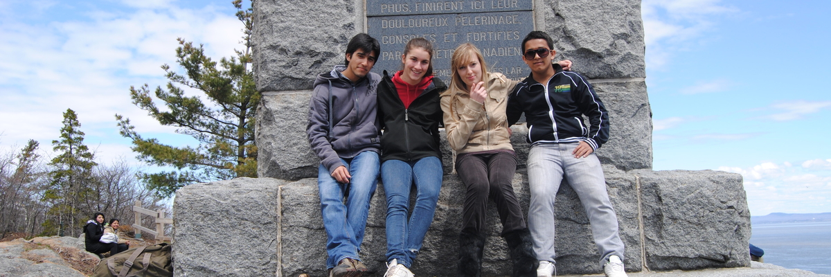Un groupe d'étudiants posent devant un monument à Grosse Île avec des étudiants de la francisation.