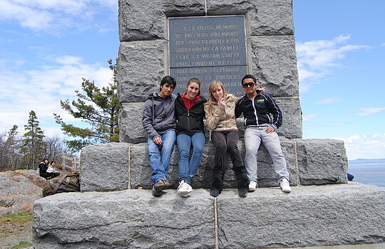 Un groupe d'étudiants posent devant un monument à Grosse Île avec des étudiants de la francisation.