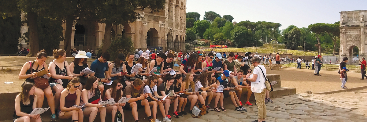 Un groupe d'étudiants assis devant le Colisée de Rome en Italie.