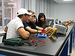 Des étudiants collaborent sur une machine en laboratoire.