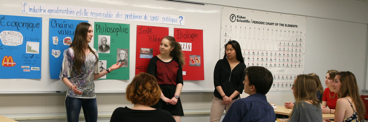 Des étudiantes font une présentation orale devant leur camarade en classe.