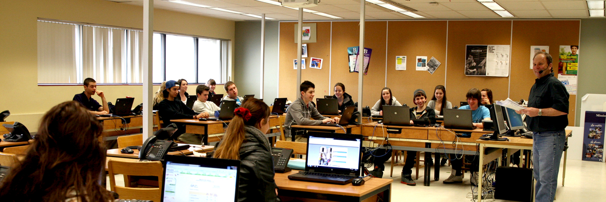 Un professeur avec micro-casque est debout devant sa classe.