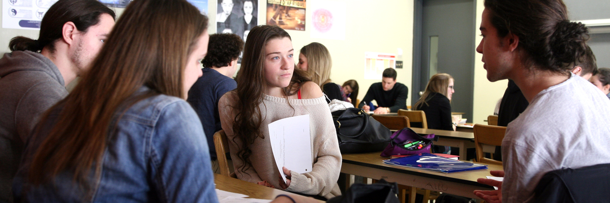 Des étudiants en discussion autour d'une table en classe.