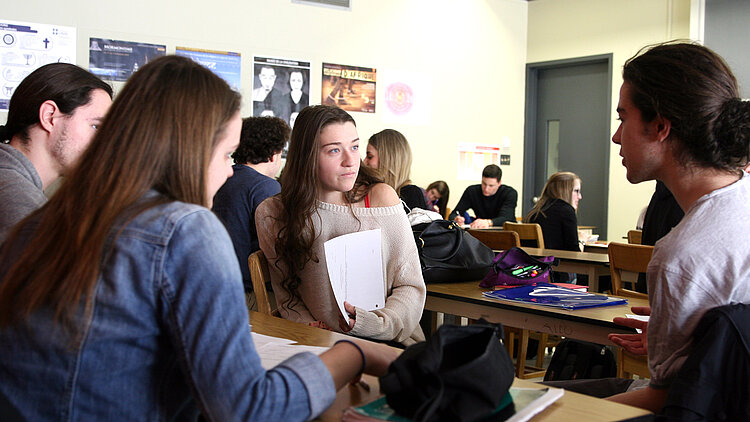 Des étudiants en discussion autour d'une table en classe.