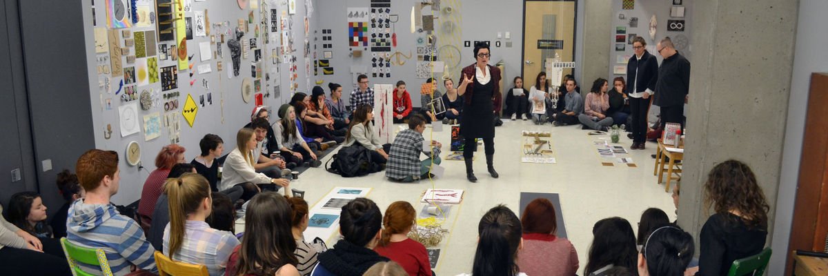 Une professeure donne une explication à un groupe d'étudiant dans une salle d'exposition.