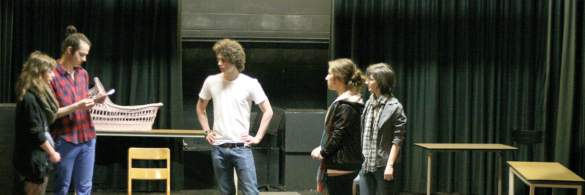 Des étudiants répètent une scène de théâtre sous les explications de leur professeur.