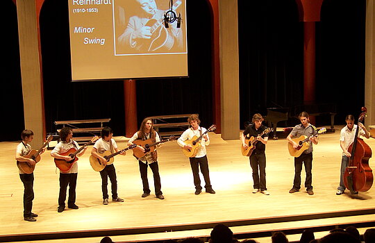 Des étudiants jouent de la guitare sur une scène.