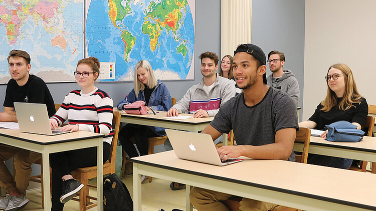 Des étudiants écoutent leur professeur en classe.