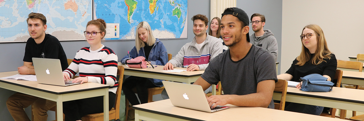 Des étudiants écoutent leur professeur en classe.