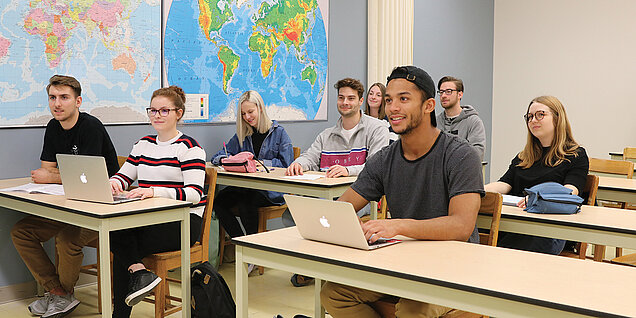 Des étudiants écoutent leur professeur en classe.