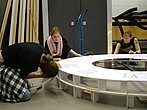 Des étudiantes travaillent à fixer les morceaux d'une horloge géante.