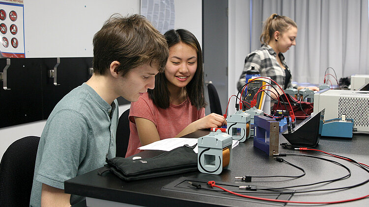 Deux étudiants travaillent sur un circuit électrique.