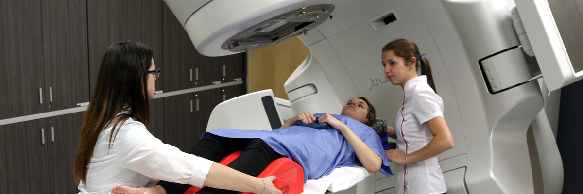 Des étudiantes placent une patiente sur un accélérateur linéaire.
